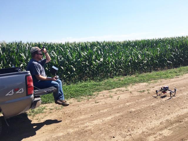 内特·汤普森准备发射一架无人机，用于NCR sre资助的农场研究项目，评估使用无人机传感器进行季节氮管理。(摄影:Gary Lesoing)