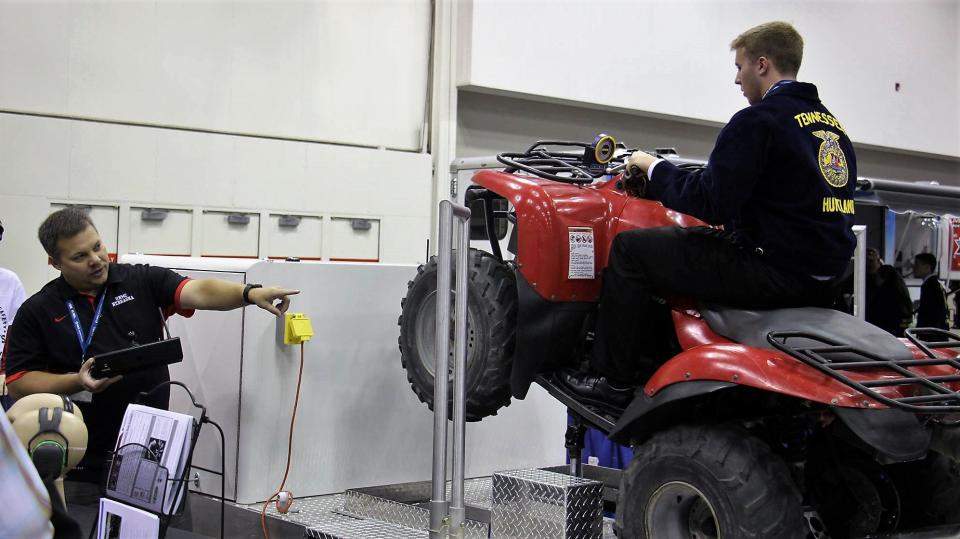 图1. Aaron Yoder在国家FFA公约中使用ATV模拟器提供安全培训。Yoder将担任青年拖拉机安全和危险职业课程的讲师之一。