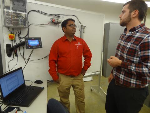 生物系统工程助理教授Santosh Pitla(左)与BSE研究生John Evans谈论他们正在教授的课程，学生们探索拖拉机操作数据的访问和分析。