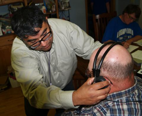 UNMC公共卫生中心的一名研究人员与内布拉斯加州的一名农民合作，为他们配戴保护性耳罩。