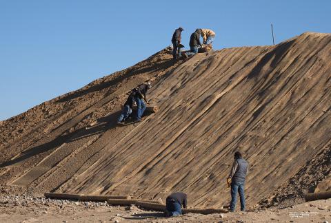 灌溉区工作人员铺设织物垫，以减少挖掘土壤的侵蚀。