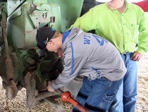 两名青年正在练习拖拉机PTO驱动装置的正确连接程序。链接至全文“青少年农场/牧场工人拖拉机安全培训课程”